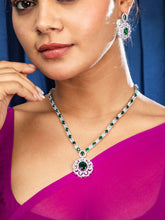 Women wearing beautiful pendant set design featuring green stone necklace with floral pendant and matching earrings.