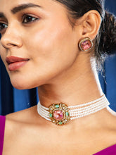 Close-up of a woman wearing a white pearl necklace with pink gemstones against a blue curtain background.