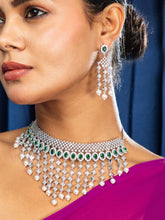 Woman wearing a sparkling necklace and earrings against a blue curtain background