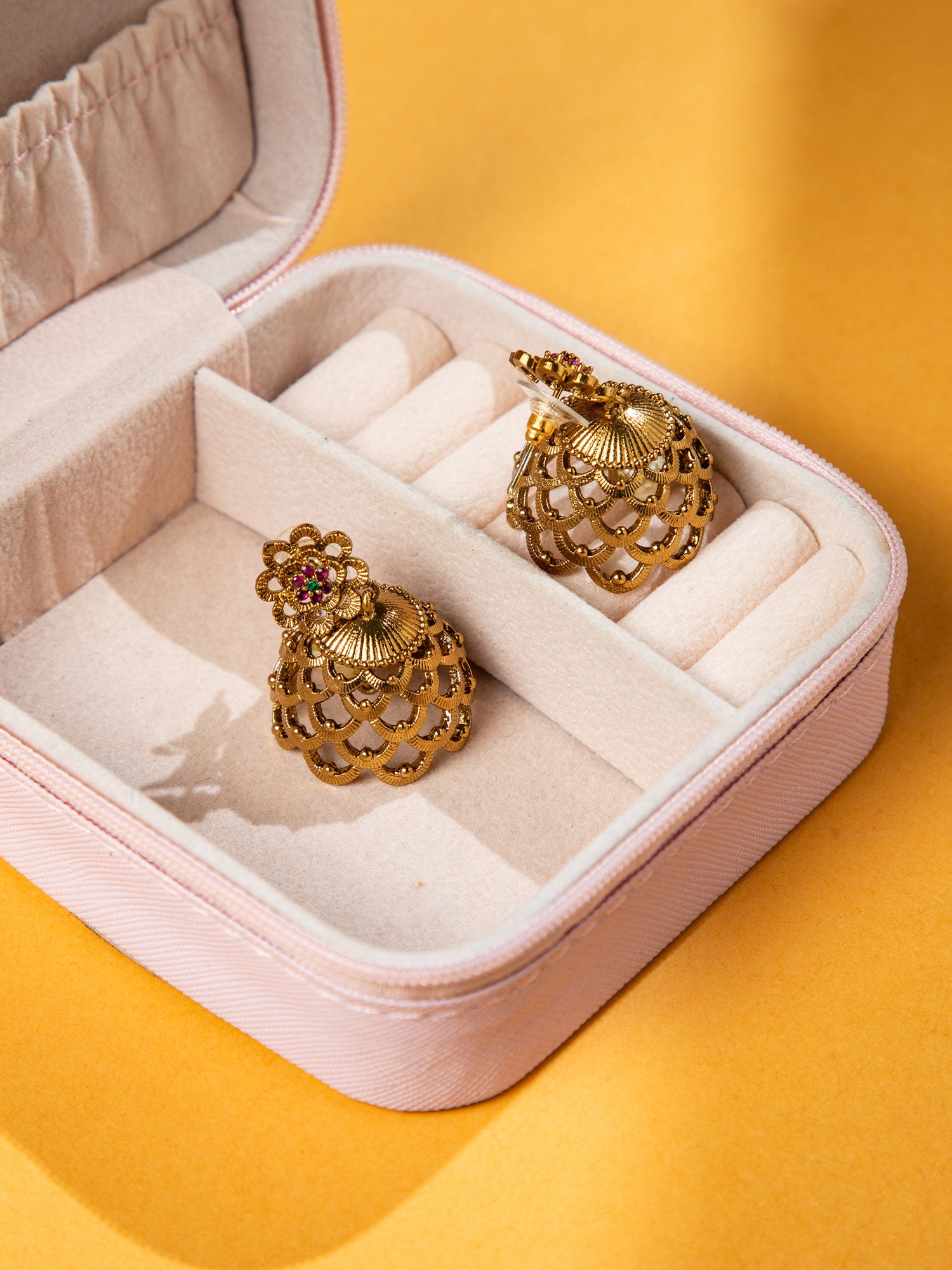 Gold earrings in a jewelry box on a yellow background