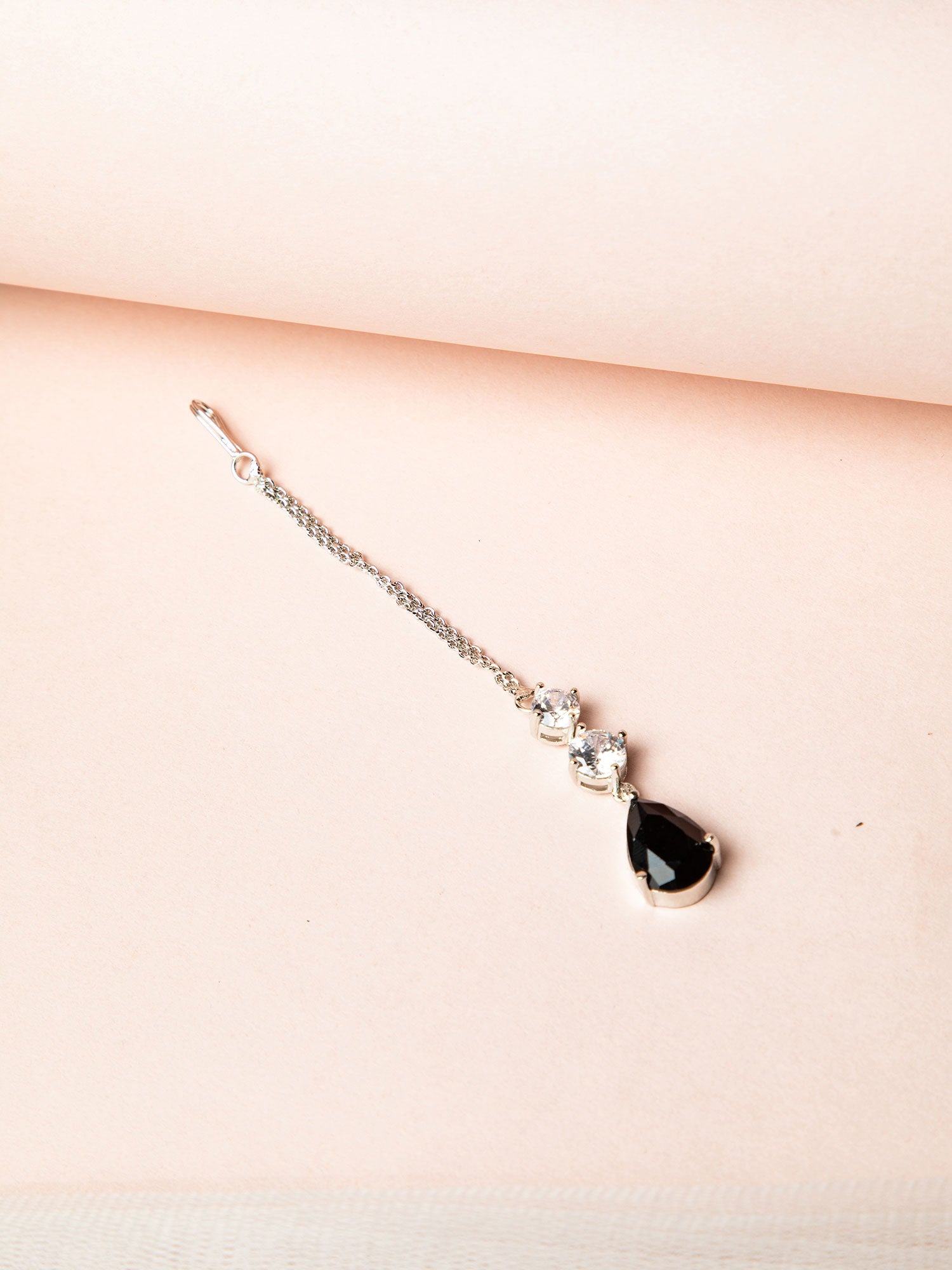 Silver Maang Tikka Design placed on a soft pink background