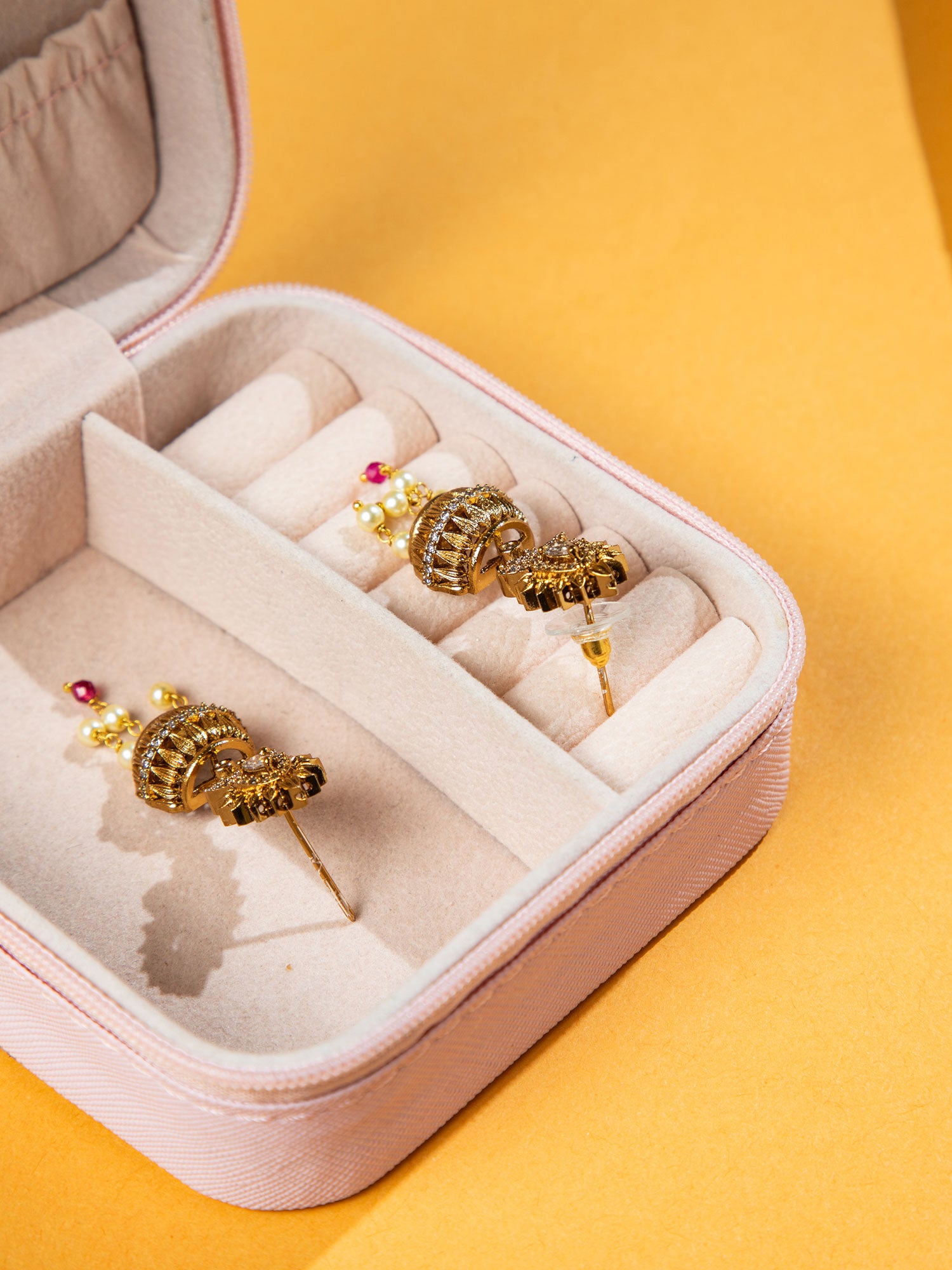white pearl earrings jhumka in a jewelry box on a yellow background