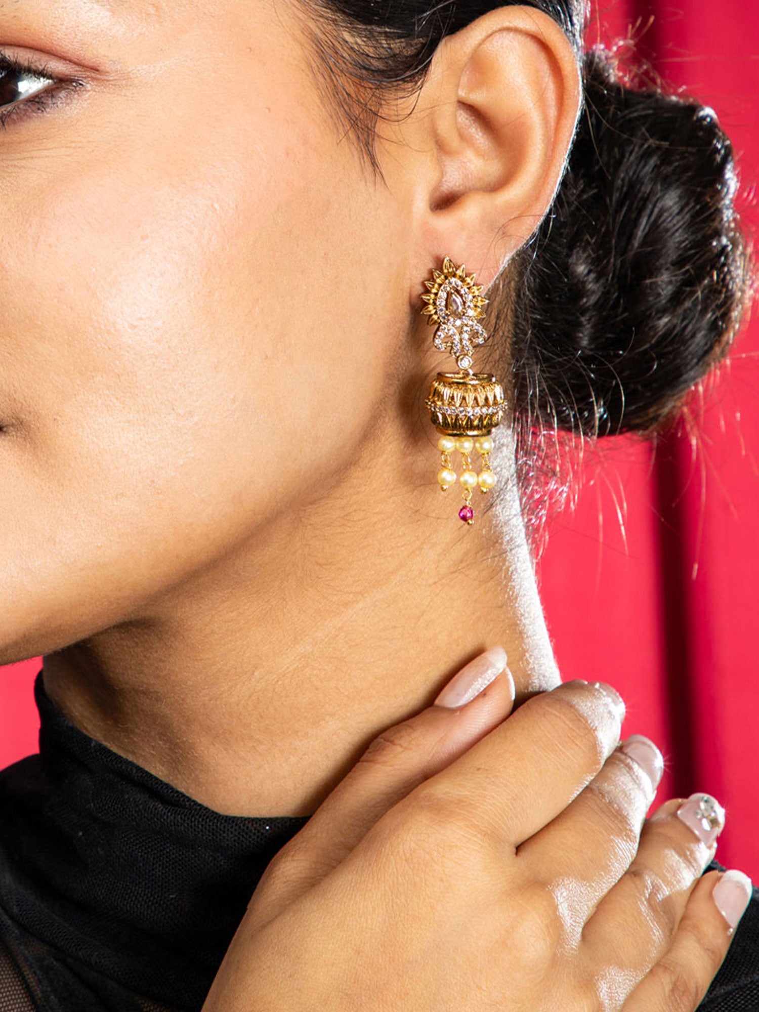 Close-up of a person wearing gold earrings with a red background