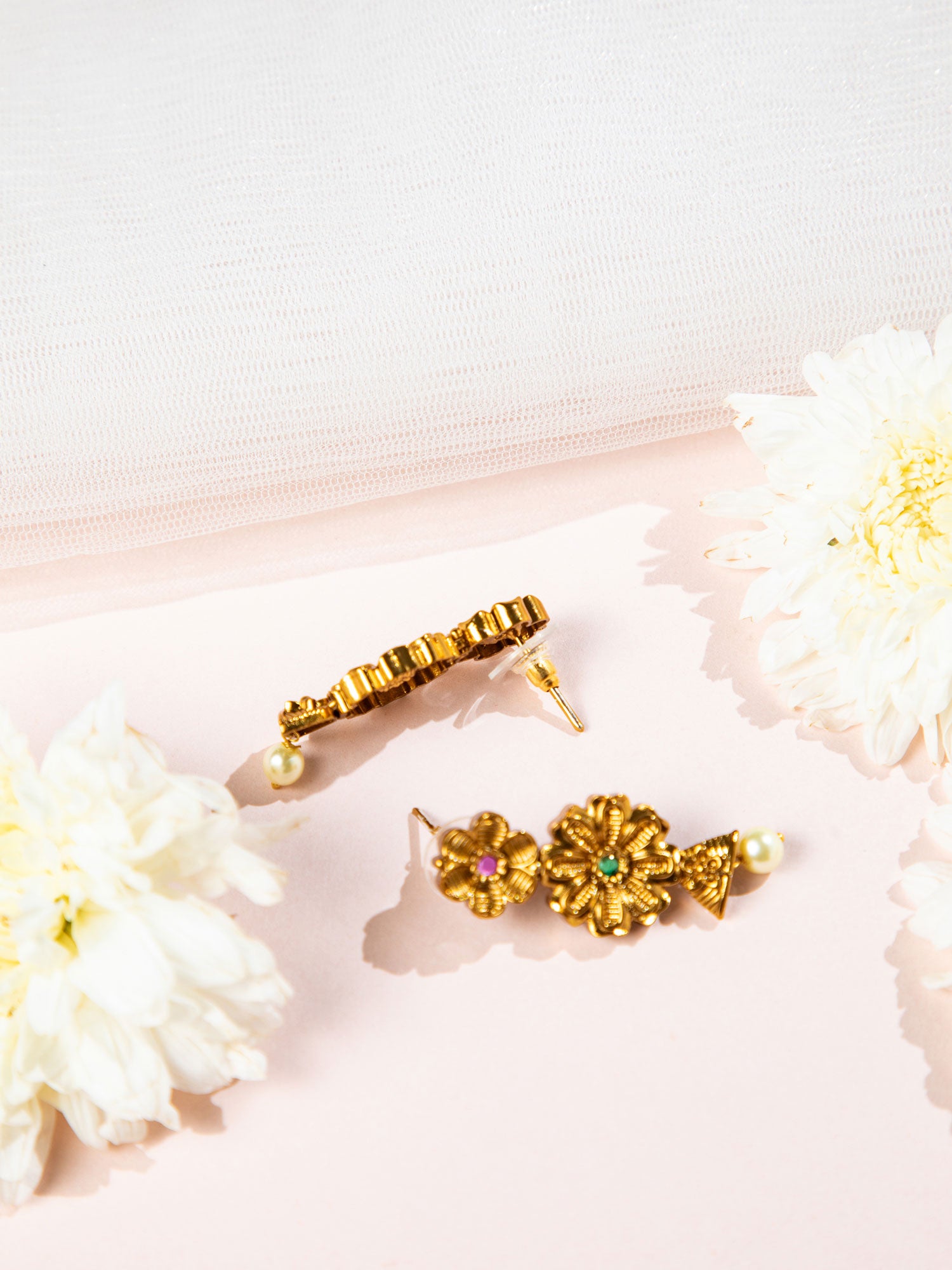 Gold temple necklace  with earrings on a pink surface with white flowers