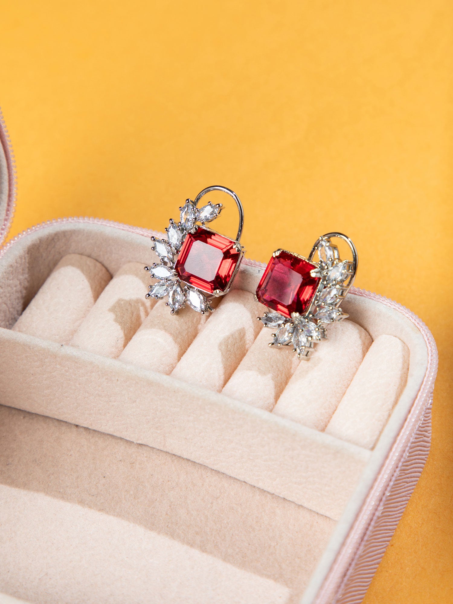 Red Rhodium Studs earrings with silver accents in a jewelry box on a yellow background