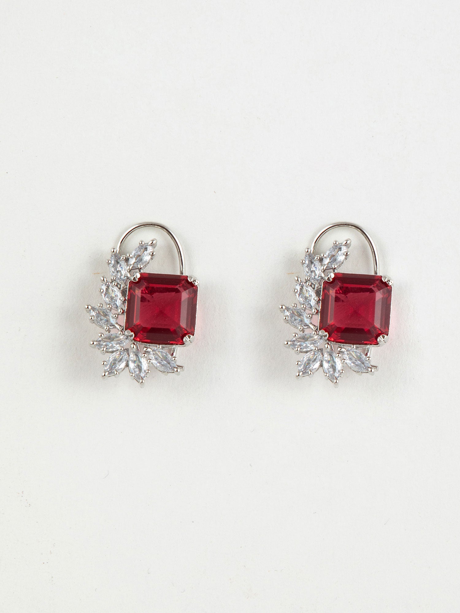 Pair of earrings with red Rhodium Studs and diamond-like stones on a white background