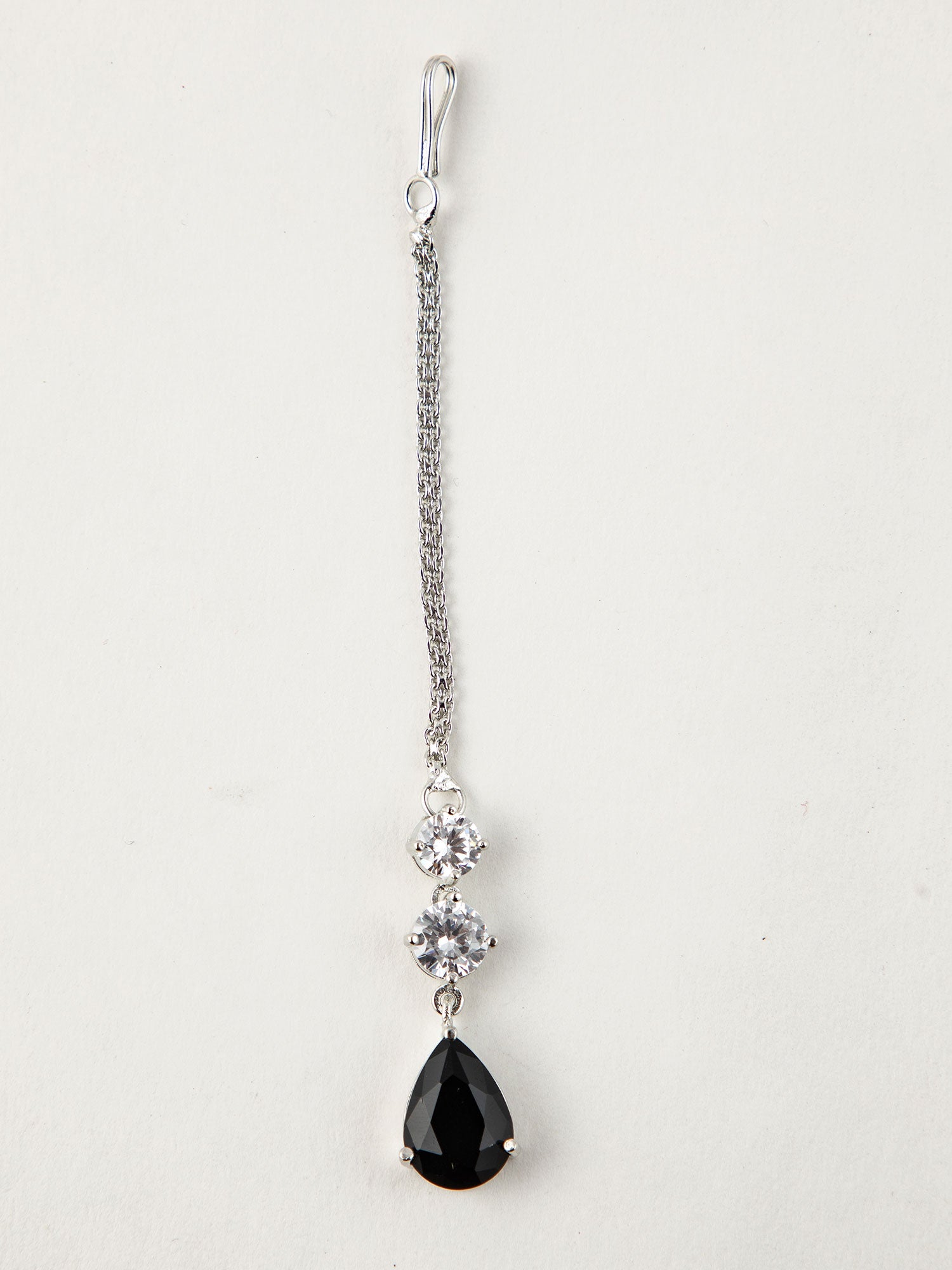 Silver Maang Tikka Design with a black teardrop stone and floral elements placed on a white background